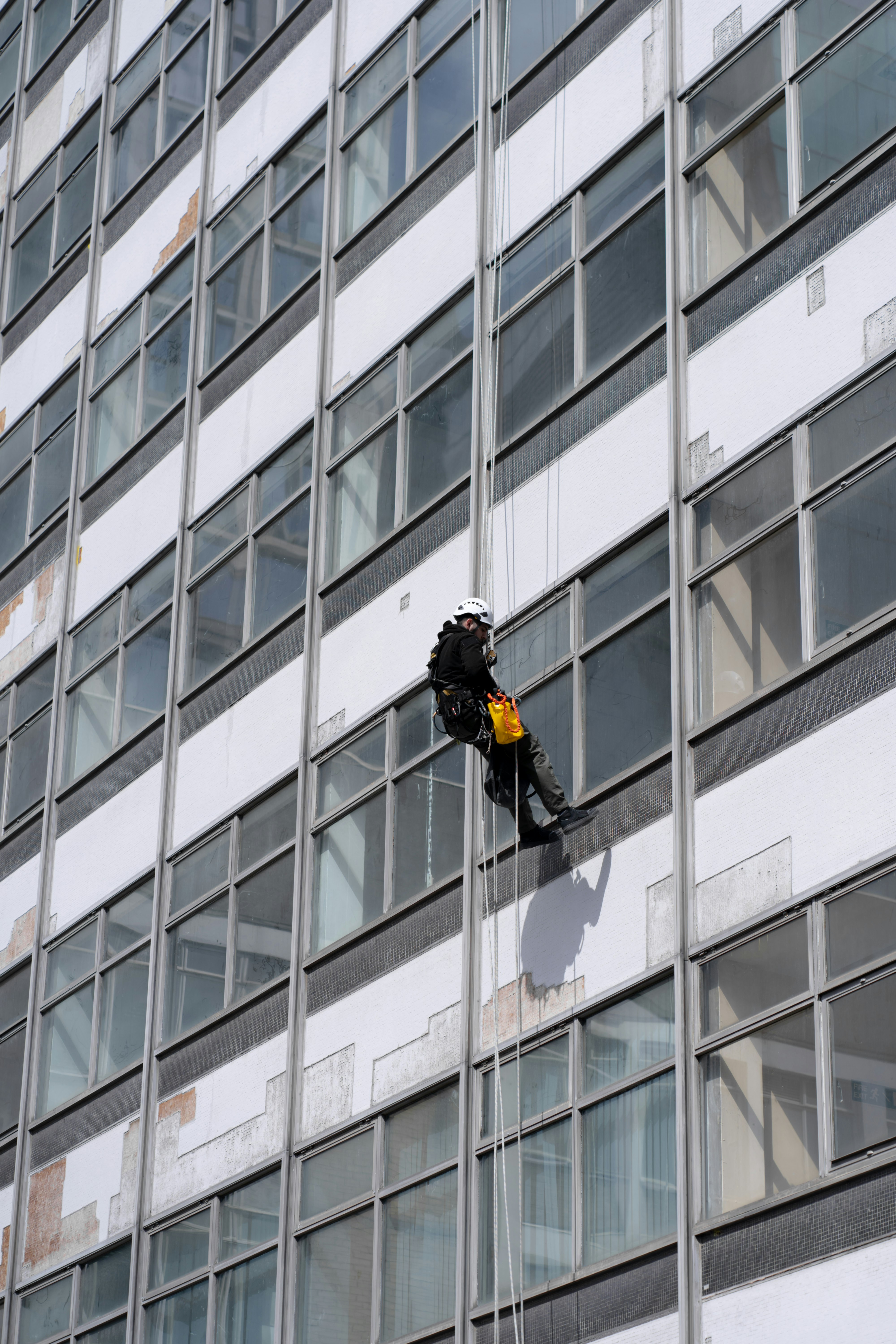 man in black jacket and black pants standing in front of glass window building during daytime